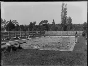 Swimming pool with diving board and boys swimming