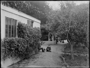 Two children [members of Nixon family?] playing with dolls in a garden, Christchurch