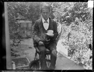 Man holding cup and saucer, seated in garden