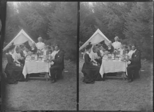 A group of men, women and children sitting at a table for afternoon tea in the outdoors