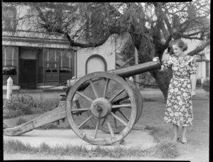 Unidentified woman standing beside a Kinman cannon at Britomart Reserve, Akaroa