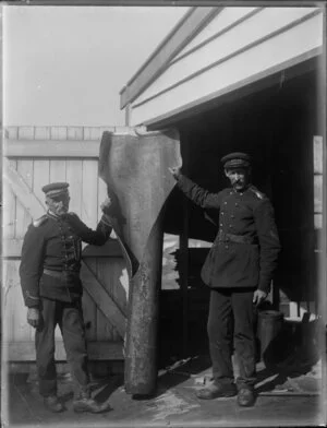 Two firemen with an object, possibly an old chimney