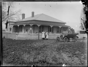 Unidentified family group in Model T Ford car with two domestic servants and child beside the house
