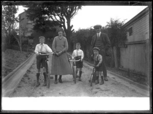 Man and woman with three children holding onto bicycles