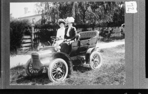 Two women sitting in front seat of Cadillac automobile