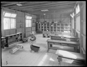 Interior of a primary school with desks, pram and storage