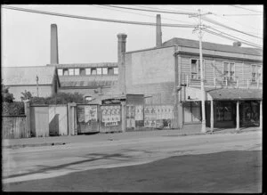 Victoria Street, Christchurch, showing shops including T Roberts, hairdresser and a fence with posters advertising shows and John Buchanan, painting contractor