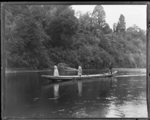 Man and children poling on an unidentified river in a canoe