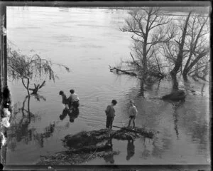Children playing by and in a flooded river, possibly the Waikato