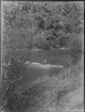 Two men in a long canoe in an unidentified river