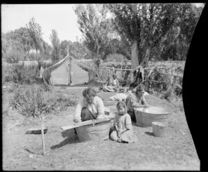 Maori family washing clothes in tubs