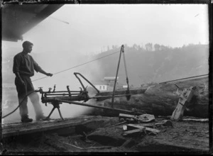 Unidentified man working on a steam crosscutter saw at a timber mill