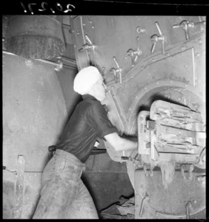 Sailor stoking a fire aboard a minesweeper, during World War 2