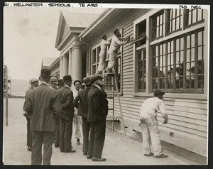 Men painting Te Aro School building with inspectors looking on, Wellington