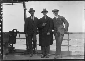Three unidentified men leaning against rail on ship's deck