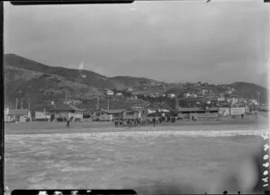 View from the sea of Lyall Bay beach as people watch men dig the trench for the cable