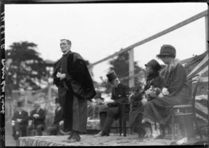 Bishop Sprott speaking, with Sir Charles and Lady Fergusson behind, Samuel Marsden School, Wellington