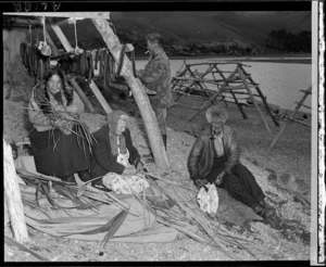 Maori men skin and dry eels while Maori women make flax baskets in which the eels will be transported when finally cured, Lake Forsyth