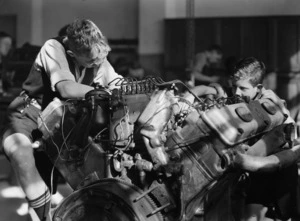 Two unidentified boys working on an engine, location unidentified