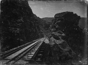 Railway line passing over a narrow gorge, and through a cutting in hilly country