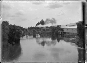 Waihou River at Te Aroha, showing "N" class steam locomotive with the Auckland to Thames Express on the railway bridge.