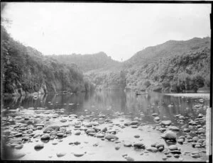 Two men in a punt on a shallow and stony tributary of the Whanganui River