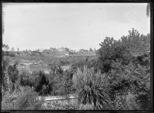View of Hamilton, Waikato Region, from the garden at Mrs Gwynne's Cottage, including the first traffic bridge, the Waikato River, and from left, St Andrew's Presbyterian Church and Le Quesne's Hotel (3 storey building), and the adjoining Hamilton Hall
