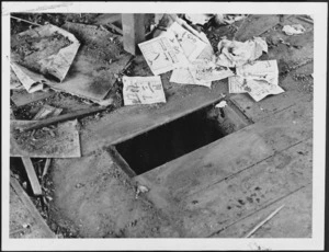 Scene taken during the demolition of a house in Haining Street, Wellington, showing a hole in the floorboards, and pakapoo tickets