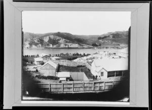 View from Rutland Stockade, Whanganui, of a backyard with people standing in it, buildings and the river