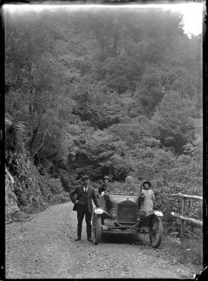 Four people with a car on the Akatarawa Road, 1923
