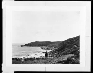 A man walking along the top of a rocky beach, unidentified location