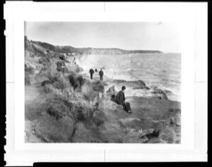 People walking along a rocky beach, unidentified location