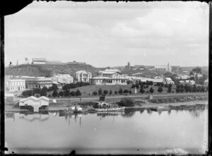 Court House and war memorial, Moutoa Gardens, Wanganui, from across the river, with the behind Rutland Stockade on hill behind. A paddle steamer and another vessel are moored alongside Taupo Quay