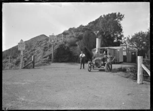 Four people with a car parked at the Summit on the Rimutaka Road, 1924