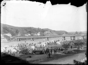 Maori at tent settlement on banks of Whanganui River near the Victoria Avenue bridge looking towards Durie Town on the southeastern shore