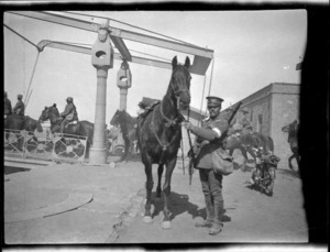 Soldier standing beside his horse.