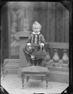 Gilbert toddler, standing on chair and holding a basket