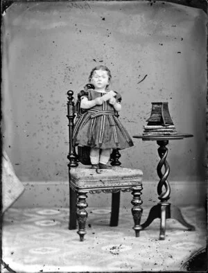 Miss Bett as a toddler, standing on a chair