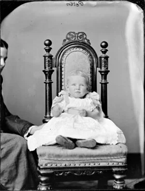 Baby Peters sitting on a chair, supported by the mother