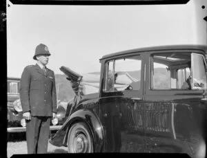 Queen Elizabeth II sitting in an open topped car with a policeman standing guard, Royal Tour 1953-1954