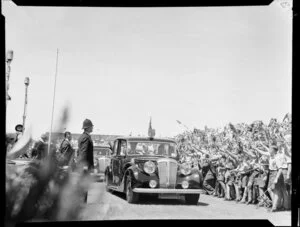 Queen Elizabeth II and the Duke of Edinburgh drive past a crowd of children waving Union Jack flags at Athletic Park, Wellington, Royal Tour 1953-1954