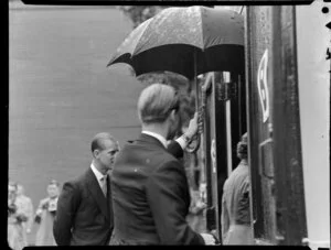 Man holding an umbrella to shield Queen Elizabeth II from the rain, Royal Tour 1953-1954