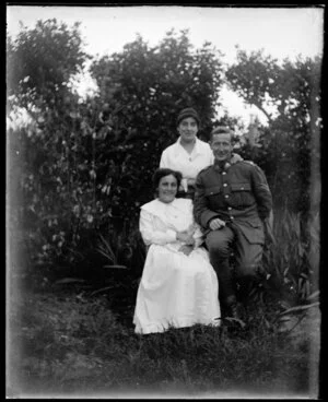 Two women and a man in uniform photographed outside