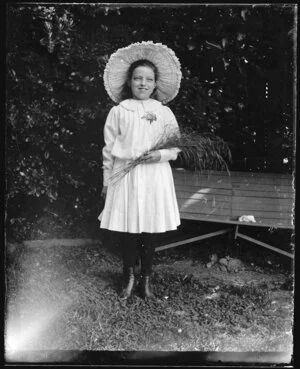 Young girl standing by garden seat