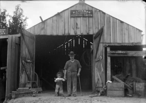 Reuben Luckman, outside his shoeing and general smithing workshop, with his young son