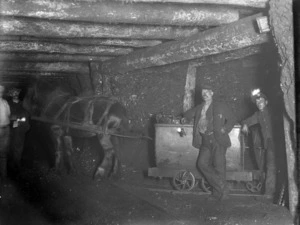 Scene inside a West Coast coal mine, showing a horse pulling a wagon of coal and three miners
