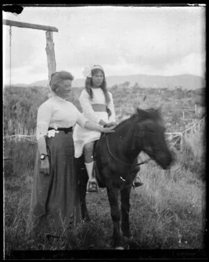 Lily May Atkinson standing next to Janet Atkinson on horseback