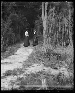 Two women standing on a path among trees