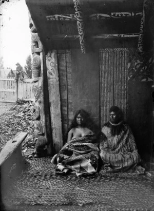 Unidentified Maori man and woman seated in the porch of a Hawke's Bay meeting house