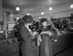 Two women in the hosiery section of a department store inspecting stockings